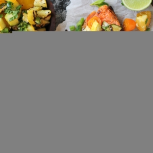 How to Perfectly Grill Salmon - the best grilled salmon on a cutting board with grilled zucchini and tomatoes on top, with sprinkles of green onions and fresh mint leaves.