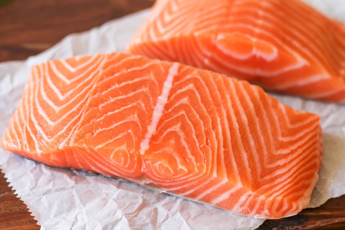 Two raw salmon filets on a cutting board, ready to use.