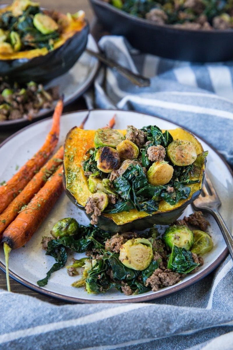 Plate with a half an acorn squash stuffed with ground beef and vegetables with a napkin to the side.