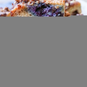 hunks of paleo blueberry coffee cake stacked on top of each other, revealing the fresh berry inside.