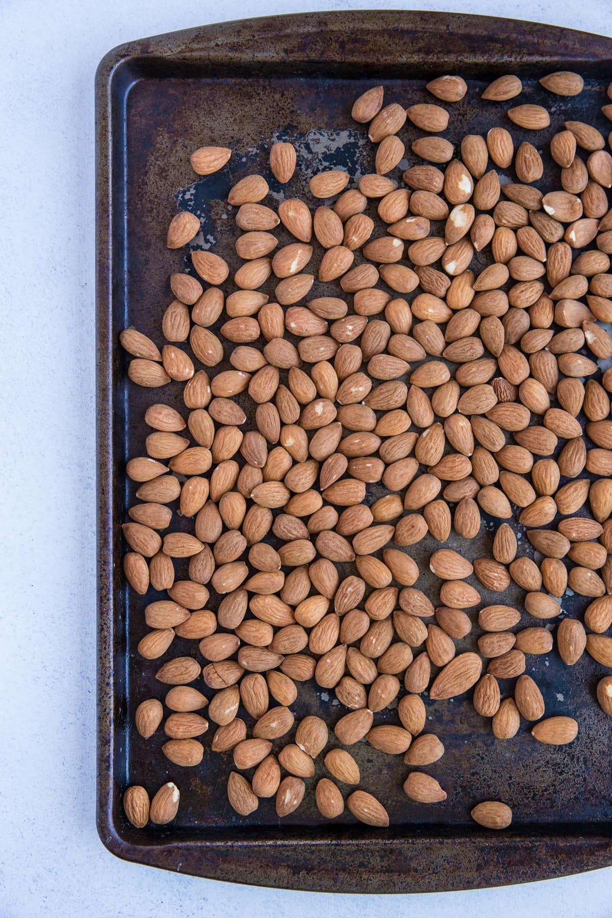Baking sheet with roasted almonds spread evenly over it.
