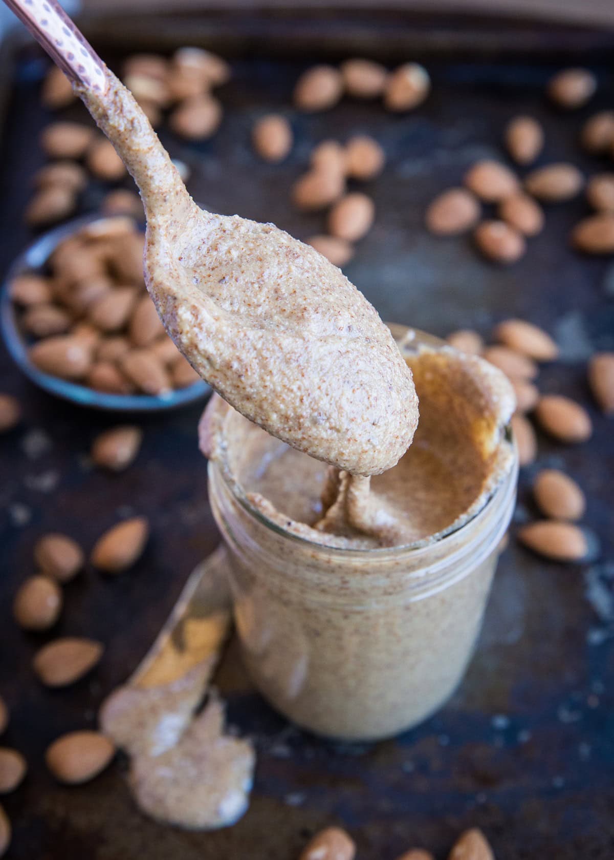 Spoon scooping some almond butter out of a jar.