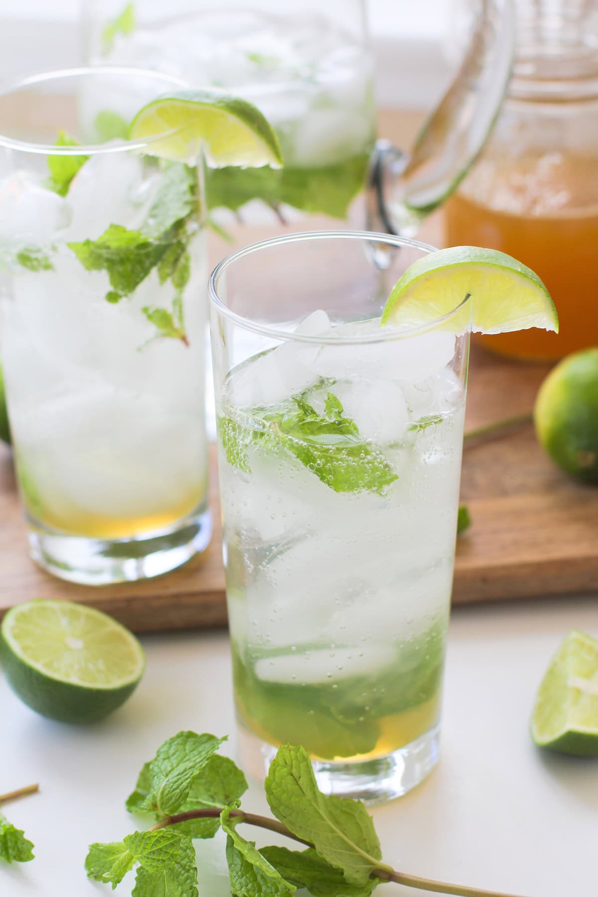 Two tall glasses of honey mint mojito cocktails with ice and fresh mint in front of the glasses. Ready to drink.