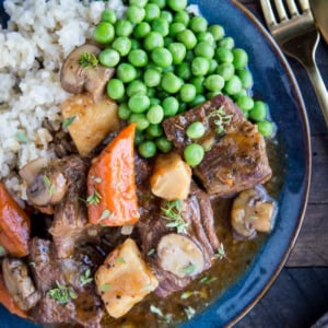 Blue plate full of beef bourguignon, rice, and peas. Ready to serve.