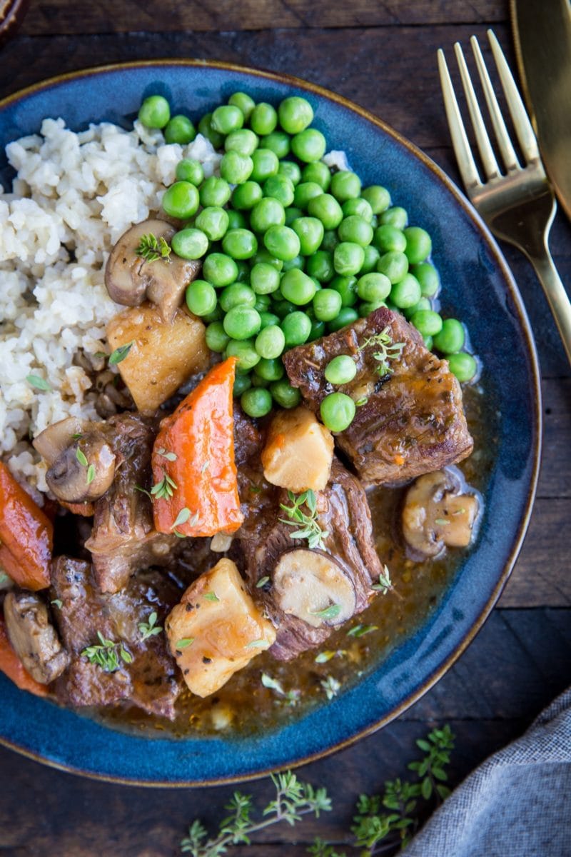 Blue plate full of beef bourguignon, rice, and peas. Ready to serve.
