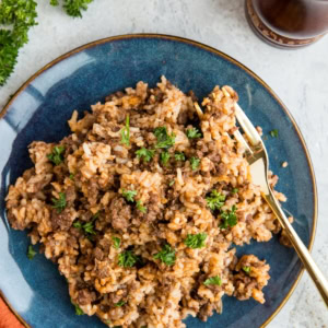Blue plate of hamburger helper with rice, sprinkled with parsley.