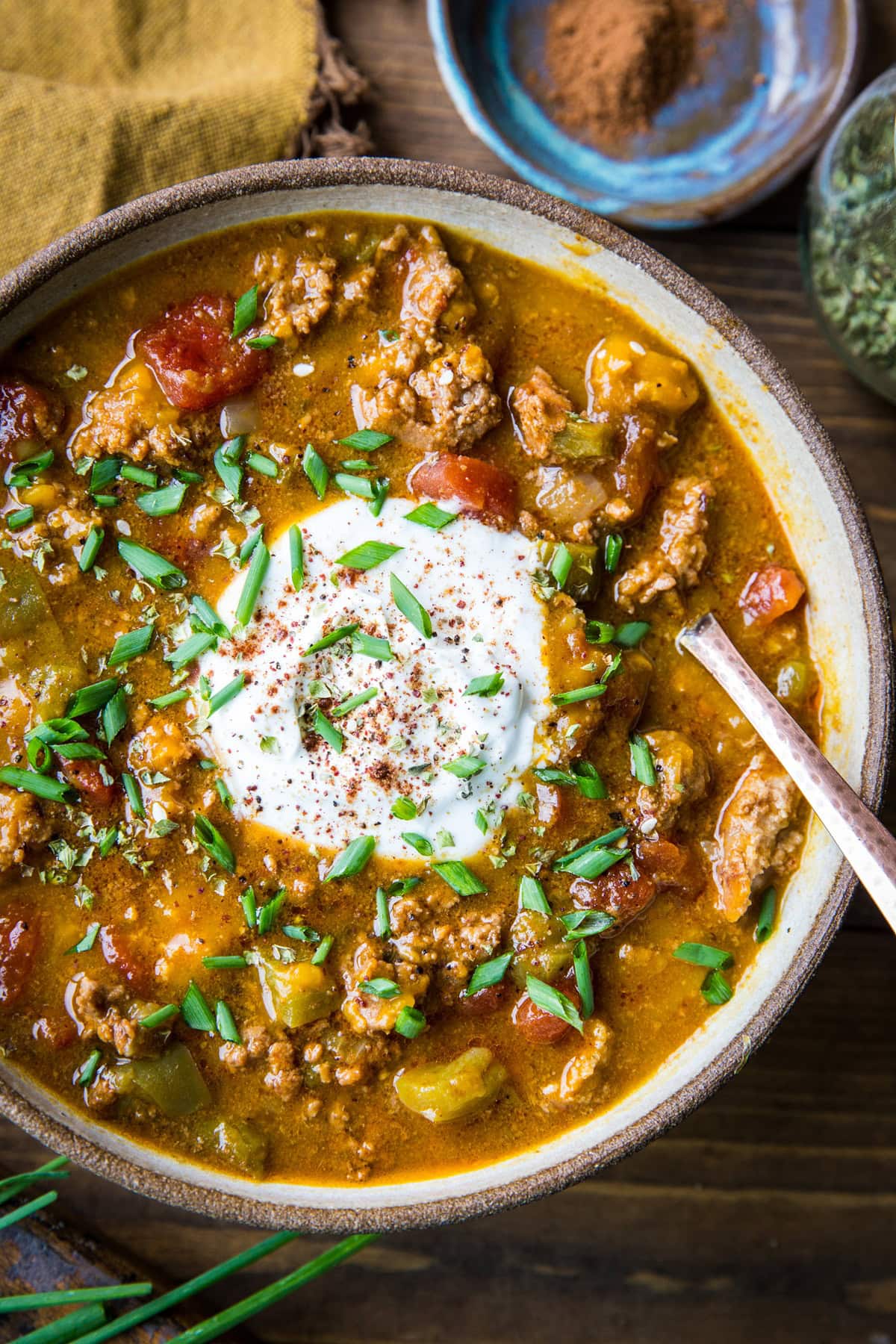 Big bowl of paleo pumpkin chili with a dollop of sour cream in the middle, sprinkled with fresh chopped chives, ready to eat.