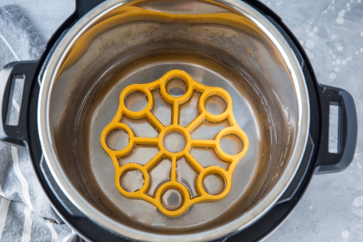 Pressure cooker with water and a silicone trivet for eggs inside.
