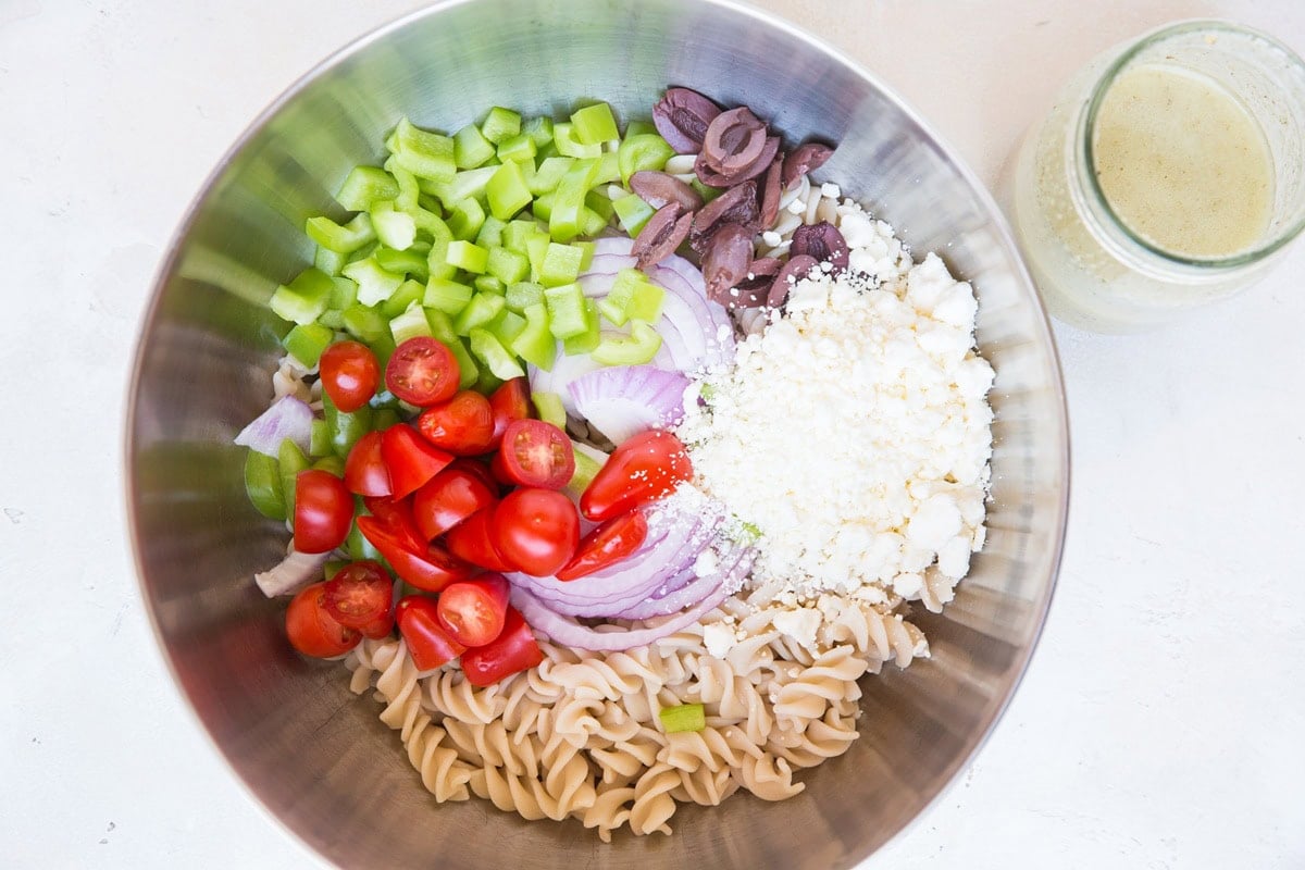 Ingredients for Italian Pasta Salad in a bowl, ready to be tossed together.