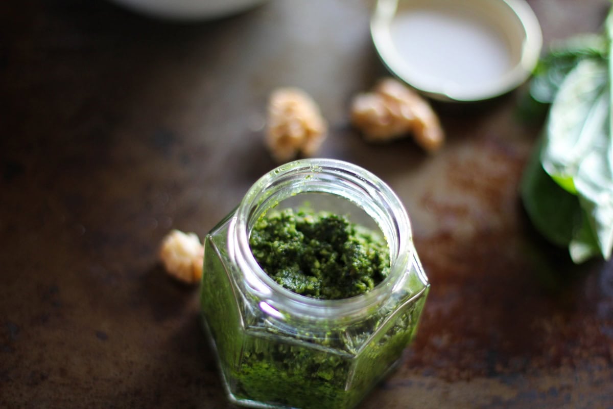 Kale Pesto | www.theroastedroot.net Kale Pesto in a jar with walnuts in the background