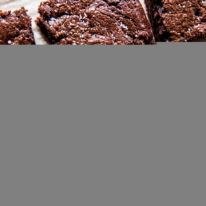 Keto brownies on a sheet of parchment paper, cut into individual slices.