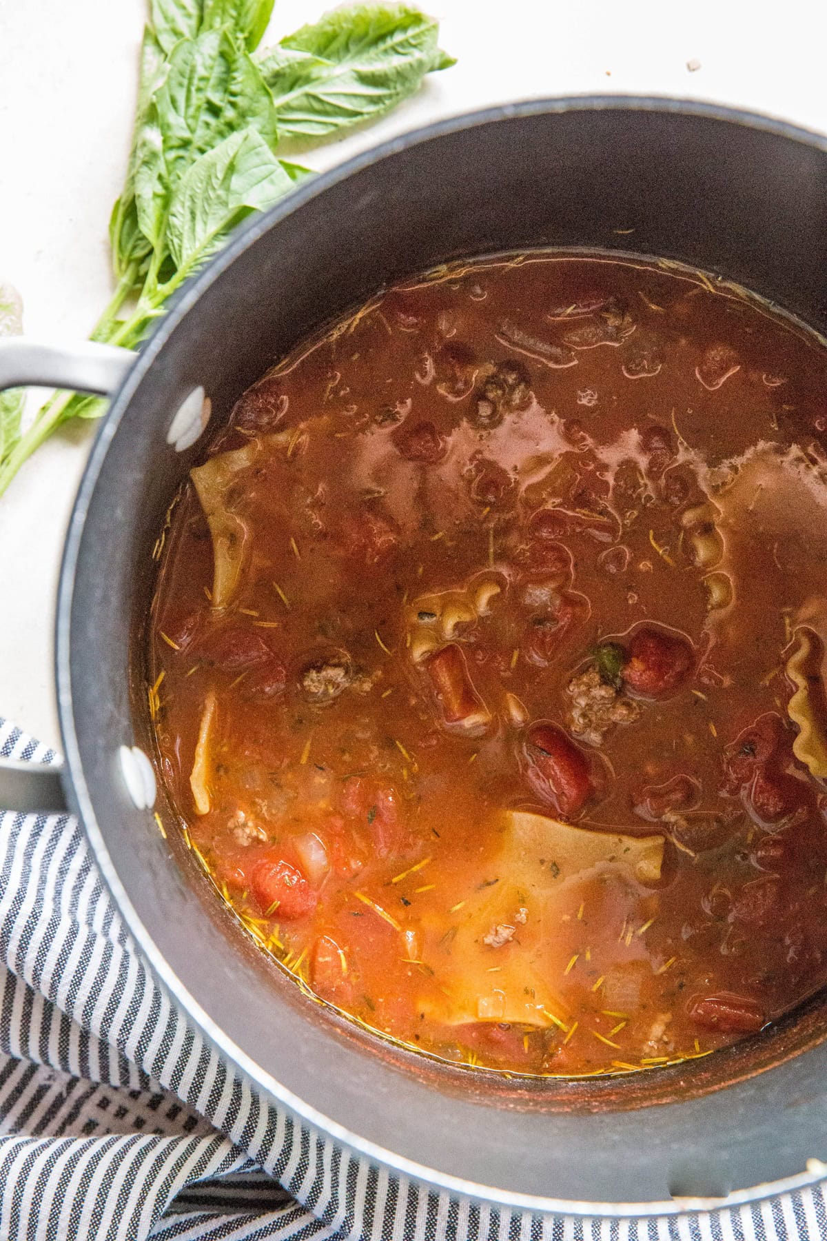 Large pot of lasagna soup with a striped napkin next to it.