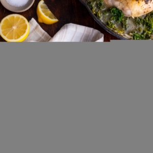 Wooden plate with Lemony Braised Chicken with Kale and the cast iron skillet with the rest of the chicken and kale. Napkins and forks around for serving.
