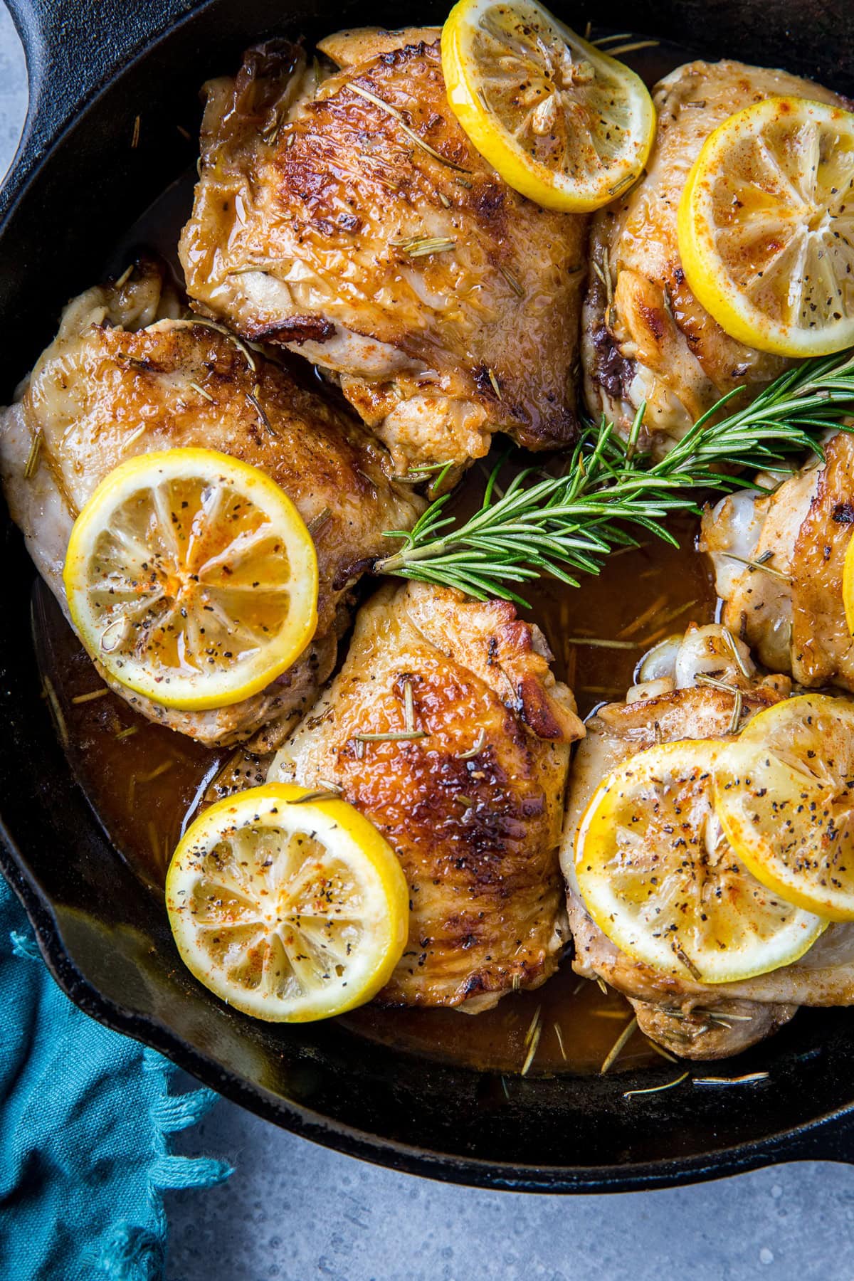 large cast iron skillet with bone-in skin-on thicken thighs inside that have been braised in braising liquid.
