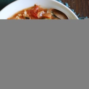 Louisiana-Style Chicken Soup with Okra in a large white bowl with brown rice to the side and a blue napkin, ready to eat