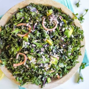 Large bowl full of massaged kale salad with pickled red onions and avocado.
