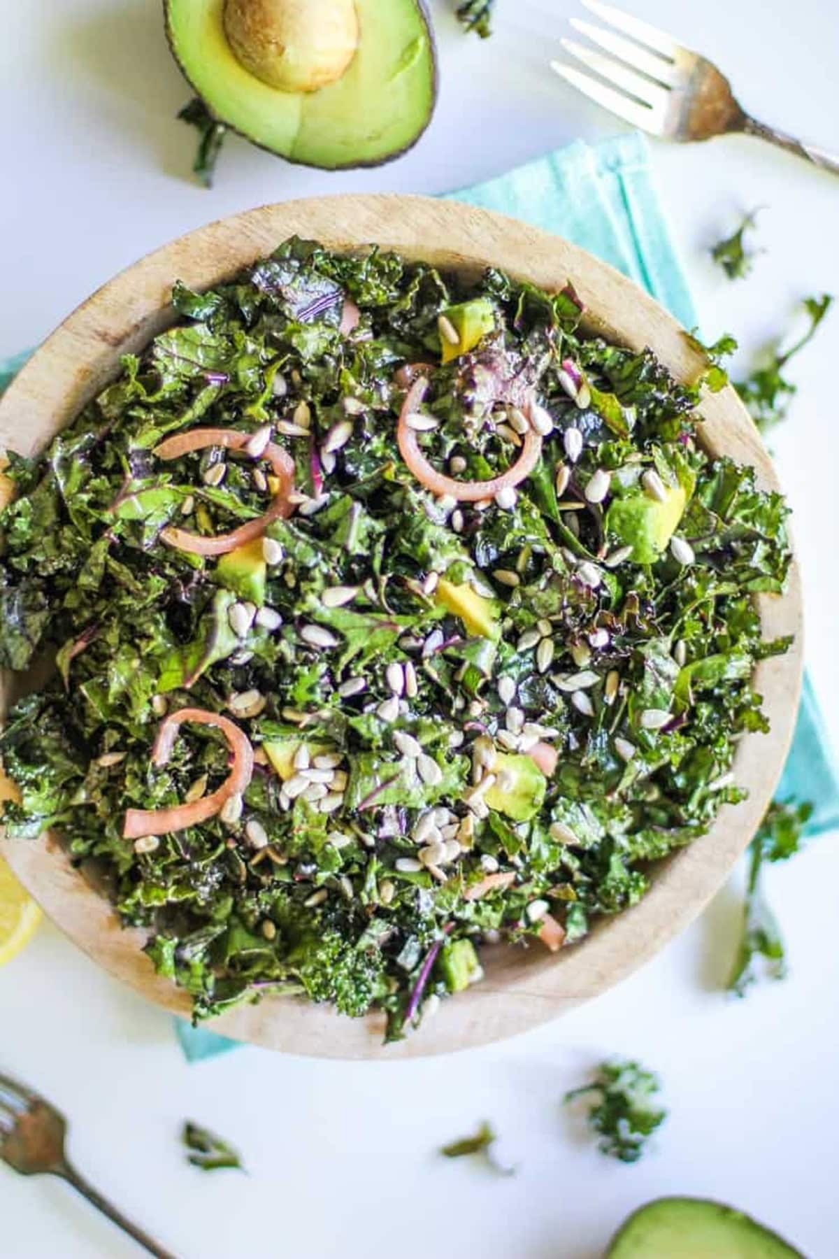 Large bowl full of massaged kale salad with pickled red onions and avocado.
