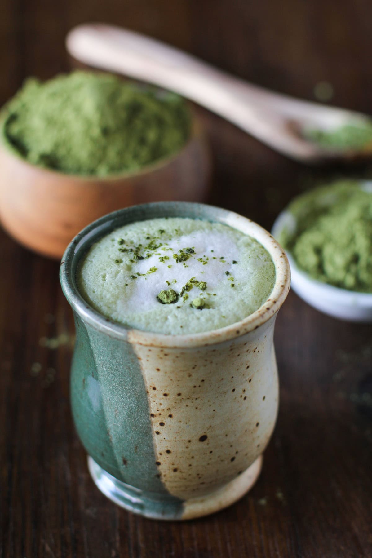 Matcha Green Tea Latte in a fancy ceramic mug with a pile of matcha in the background.