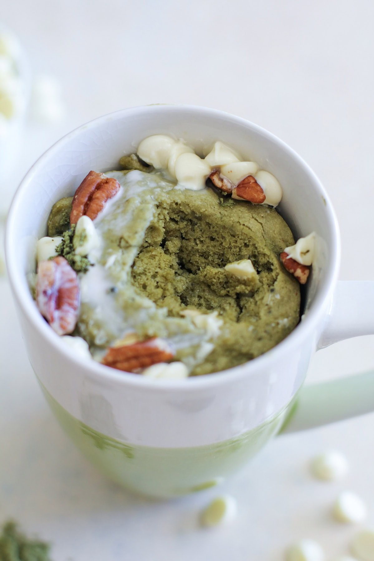 Matcha mug cake with one bite taken out of the center to reveal the fluffy inside.