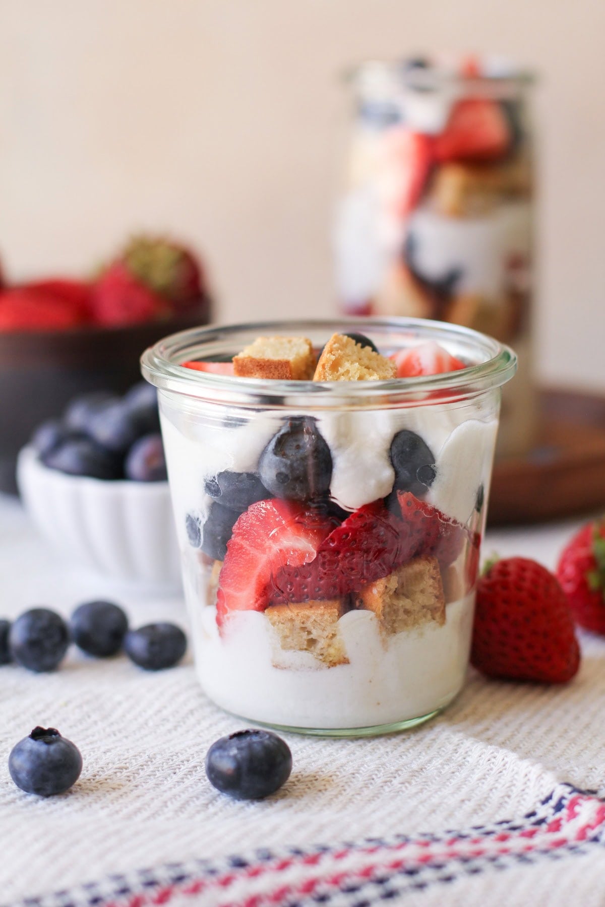 Mixed berry parfait with coconut whipped cream in a jar with chunks of pound cake. Ready to serve.