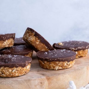 Wooden cutting board with chocolate oatmeal peanut butter cups with sea salt sprinkled on top.