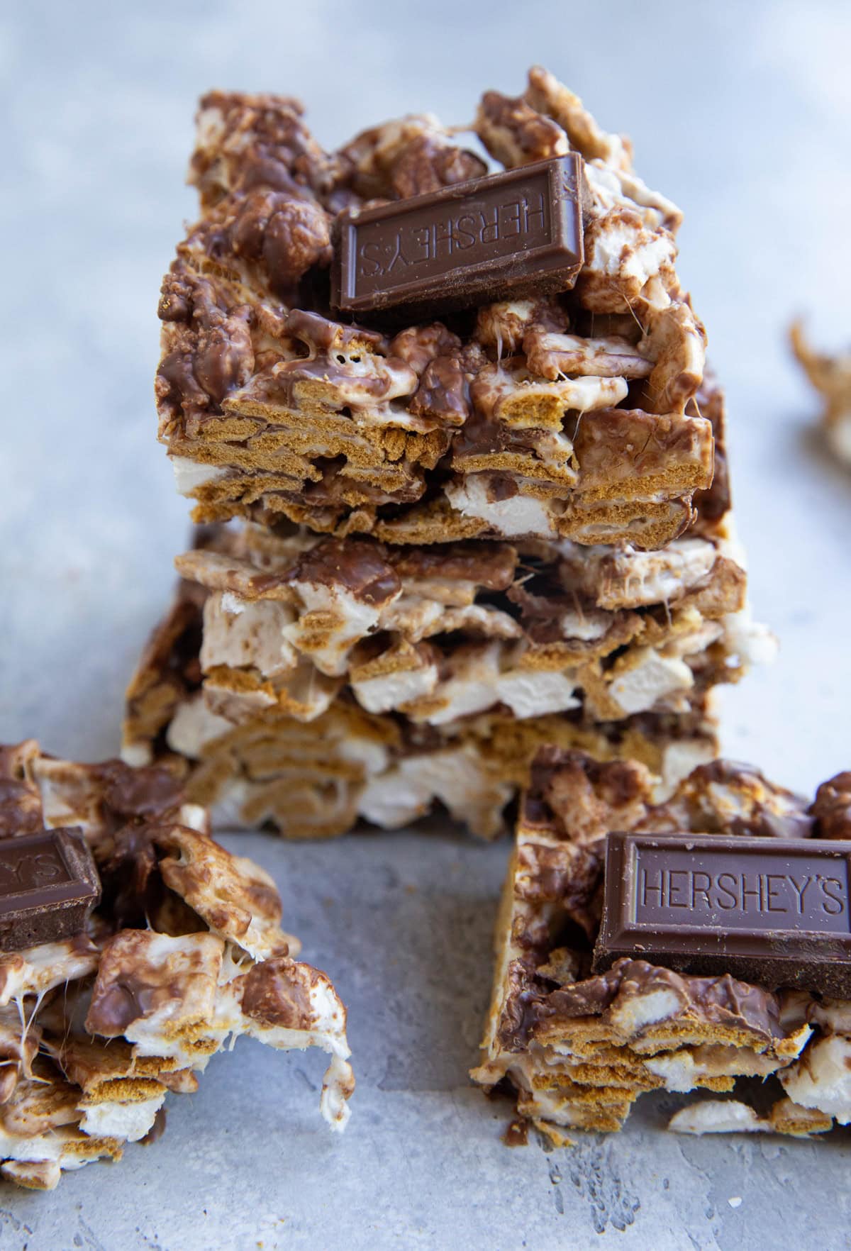 Stack of s'mores bars on a sheet of parchment paper with more s'mores bars to the side.