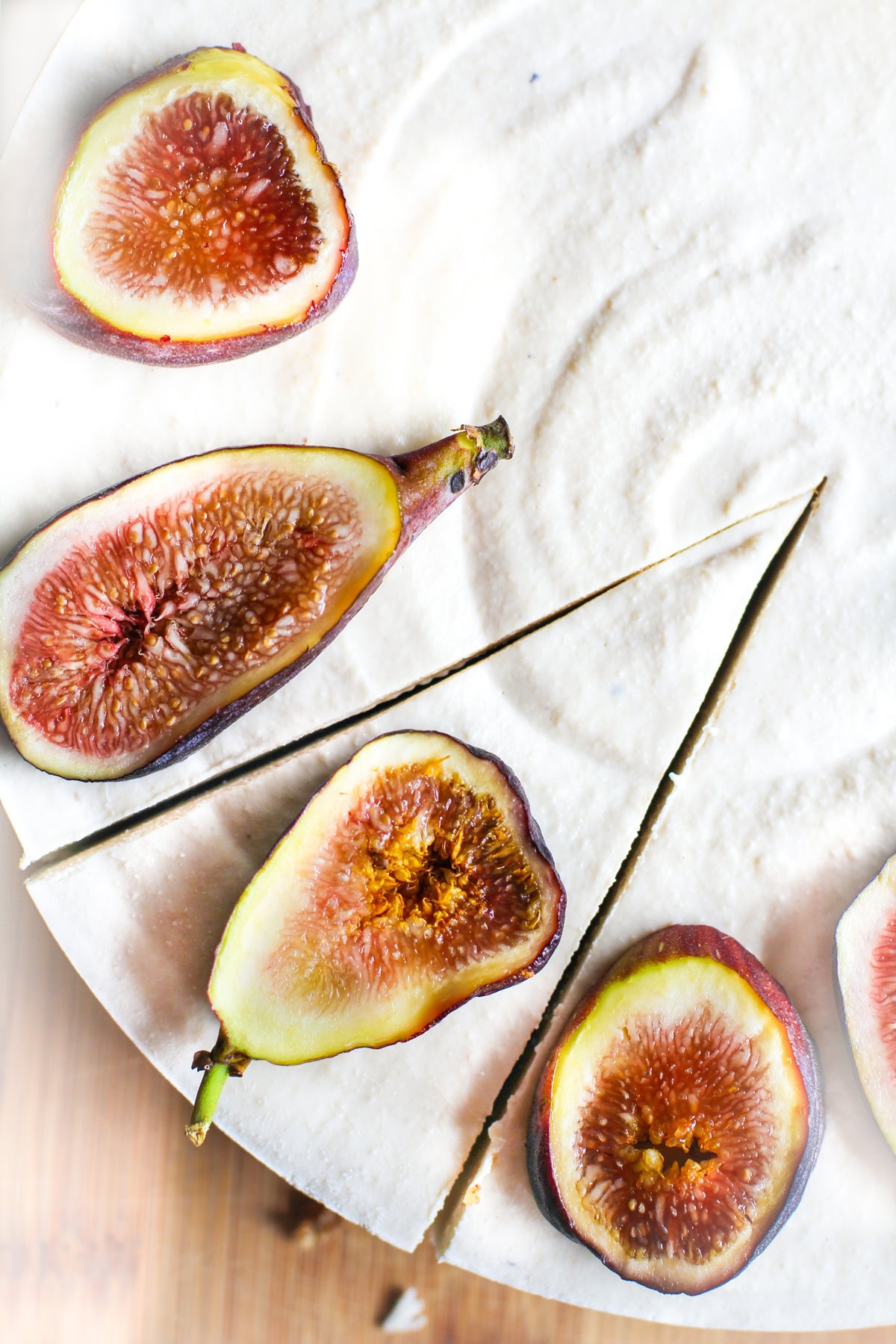 Cheesecake with sliced figs on top with a slice taken out. Photo taken from the top down to view the whole cheesecake.