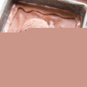 container of homemade no churn chocolate ice cream with scoop taken out and a napkin to the side.