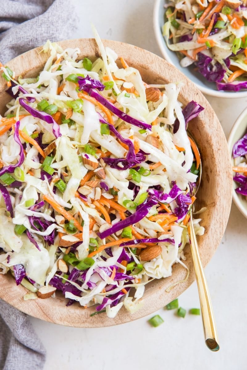 Big bowl full of homemade no mayo coleslaw with a golden spoon, ready to serve.