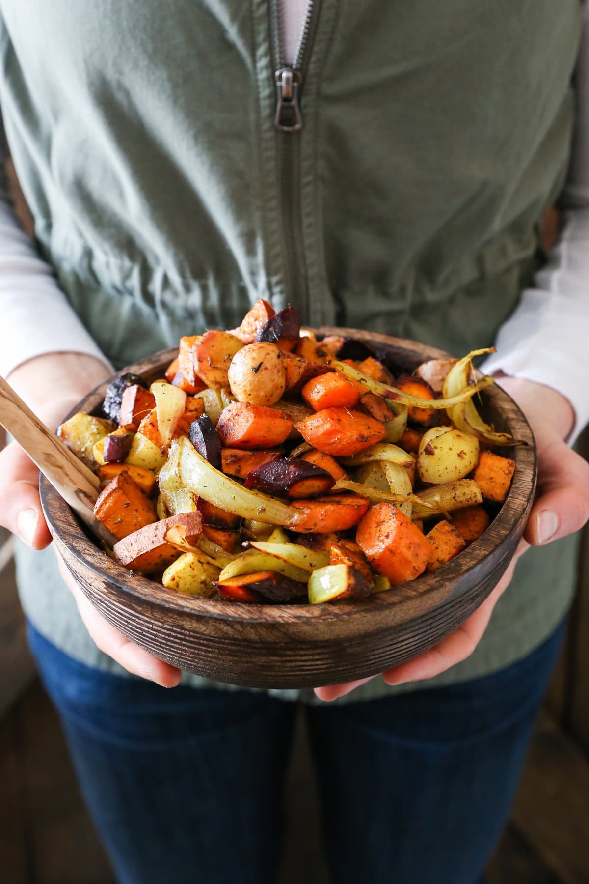 Julia Mueller holding a wooden bowl full of roasted root vegetables.