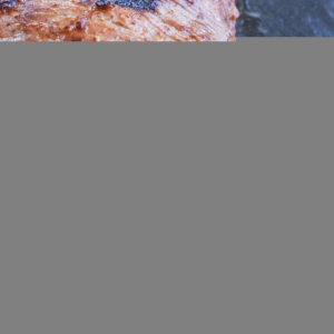 cutting board with slices of roast tri tip in its juices, ready to serve.