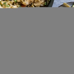 Two plates of Pad See Ew with the wok of noodles to the side.