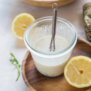Jar of lemony Caesar Salad Dressing with a whisk inside