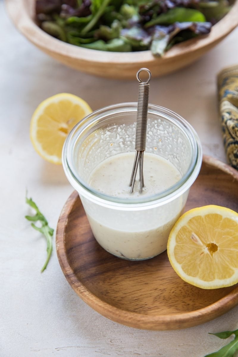 Jar of lemony Caesar Salad Dressing with a whisk inside