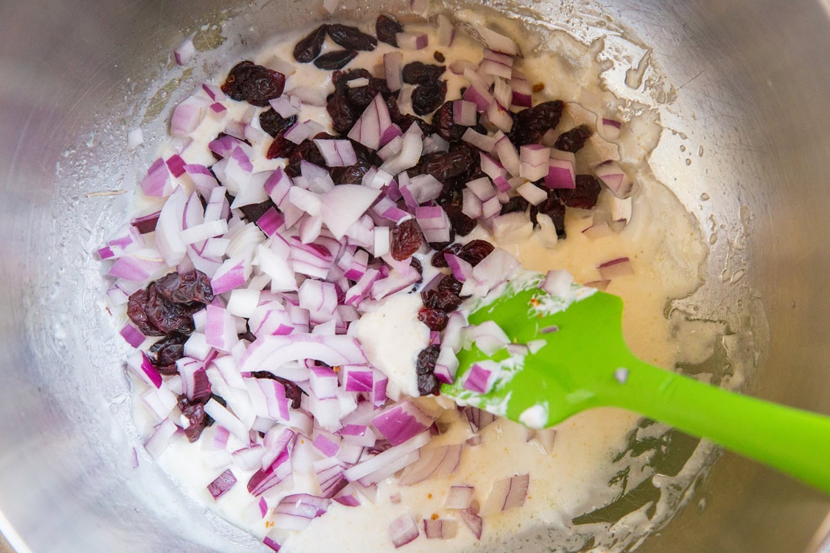 Ingredients for pea salad dressing in a stainless steel mixing bowl with a green rubber spatula to mix it all up.
