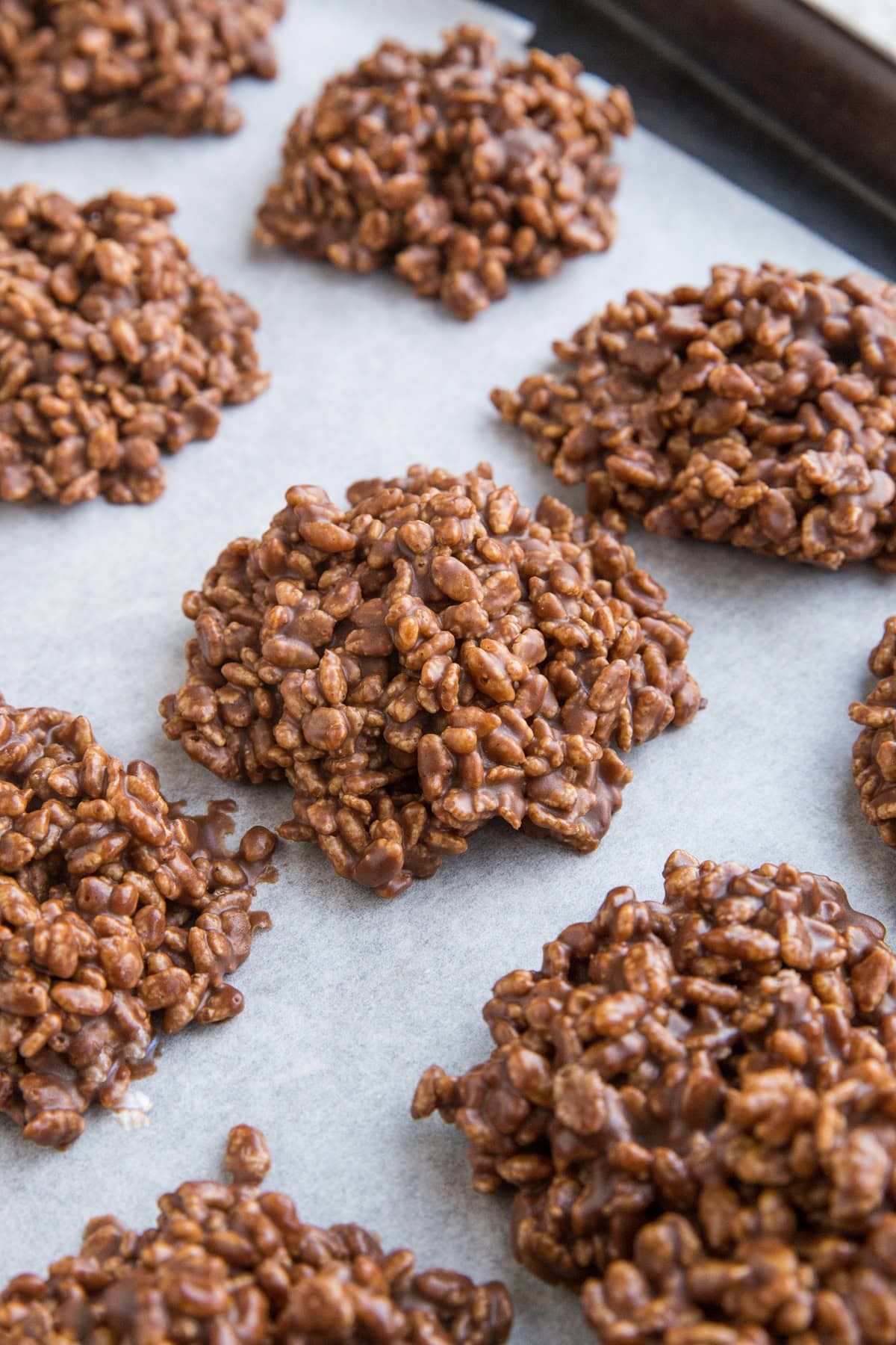 Baking sheet lined with parchment paper with chocolate peanut butter crispy rice cookies on top. Ready to eat.