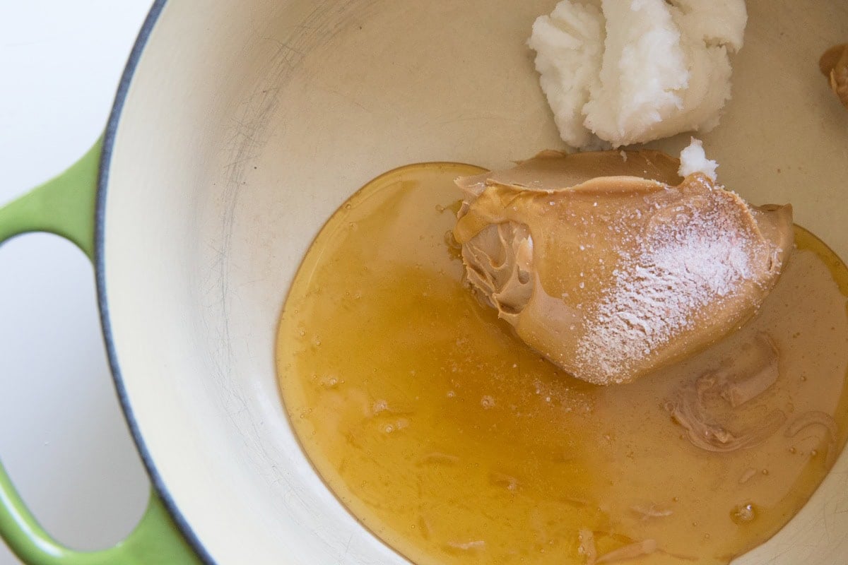 Peanut butter, honey, and coconut oil in a saucepan, ready to be melted together.