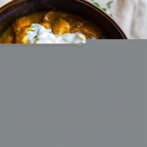 Large blue ceramic bowl full of paleo chicken chili with a spoon and a napkin, ready to serve.