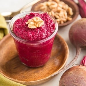 Jar of Roasted Beet Pesto with walnuts with fresh beets to the side. a flavorful, nutrient-dense pesto sauce recipe