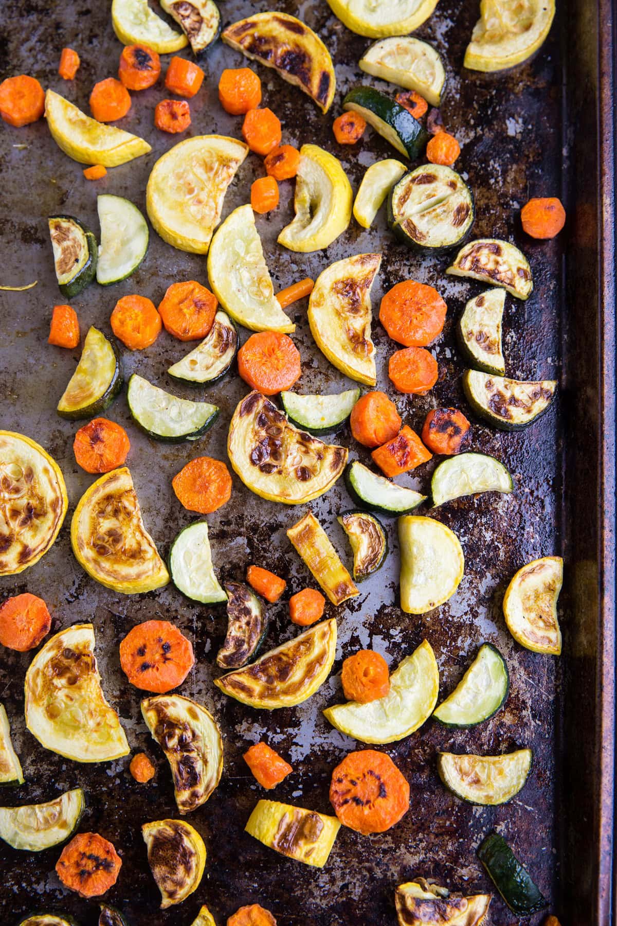 Roasted zucchini, yellow squash and carrots on a baking sheet, fresh out of the oven from roasting.
