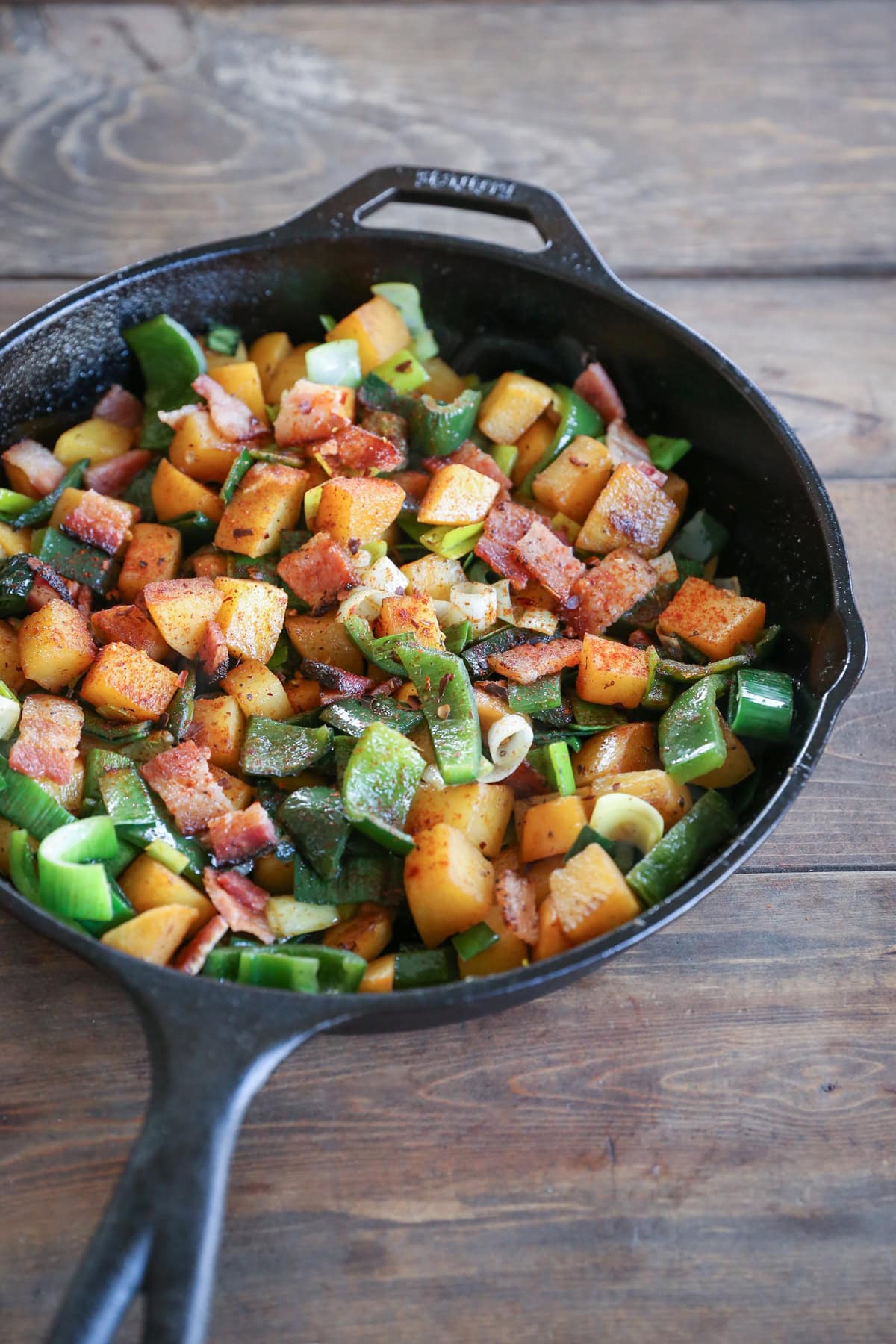 large cast iron skillet full of diced rutabagas, chiles, and bacon, ready to serve for breakfast.