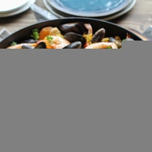 Seafood paella in a large paella pan, sprinkled with fresh parsley and ready to serve.