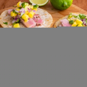Seared Ahi Tacos with Mango Avocado Salsa on a wooden cutting board, ready to eat.