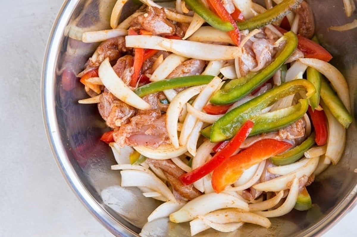 ingredients for the fajitas tossed together in a mixing bowl