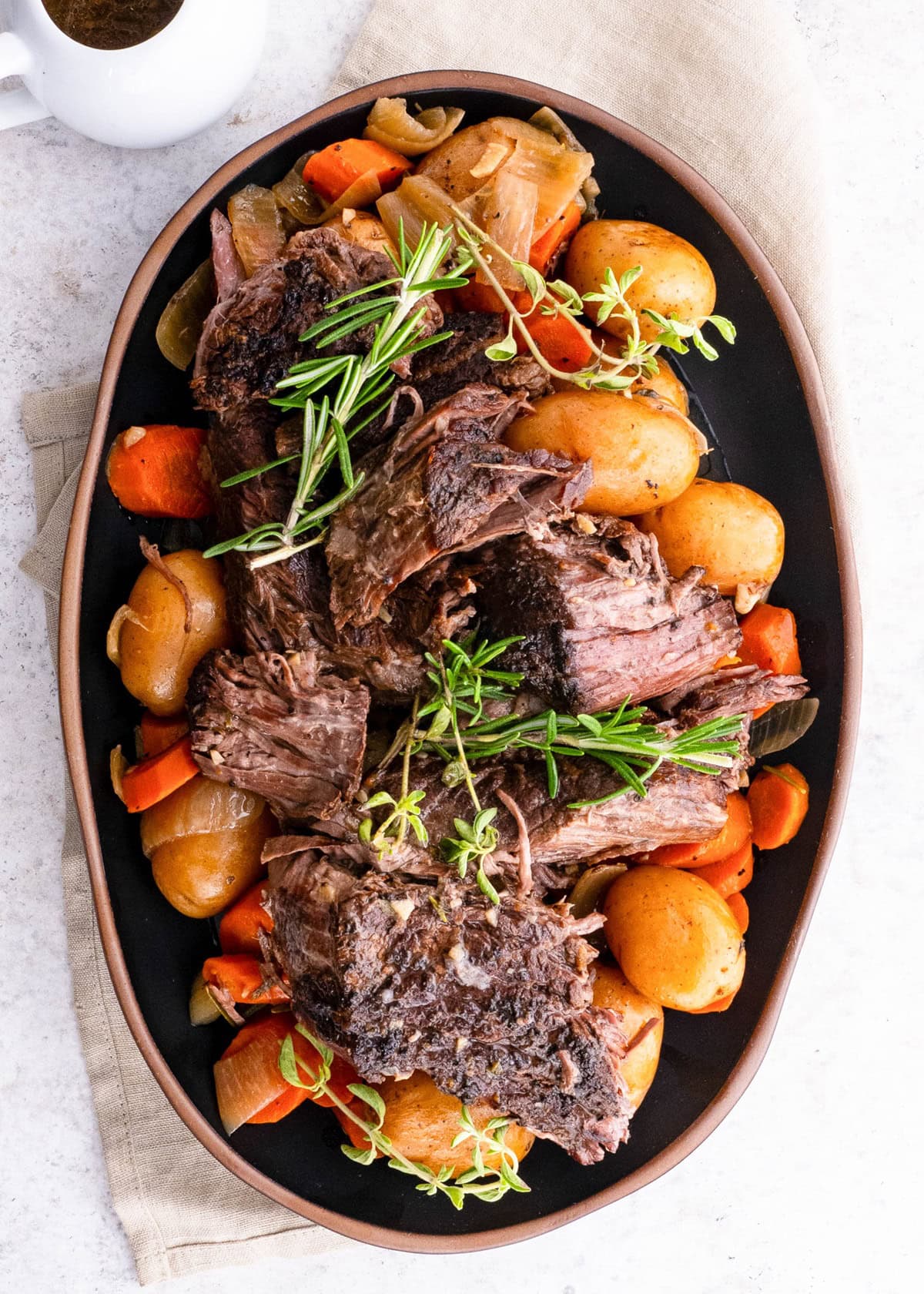 Platter of shredded beef on top of potatoes, carrots, and onions, ready to serve.