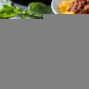 Big white bowl of spaghetti squash with red meat sauce on top and a basil leaf.