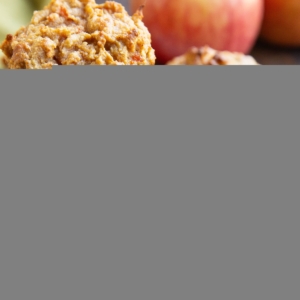 Plate of spiced apple carrot muffins with fresh apples in the background, ready to eat.