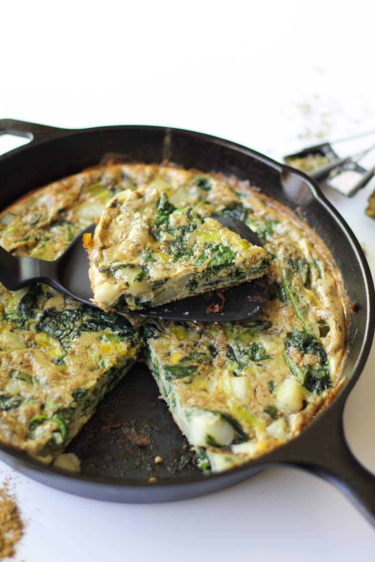 Potato Leek Frittata in a cast iron skillet with a slice taken out.