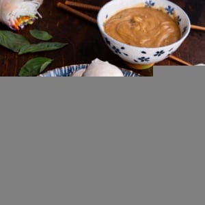 Spring rolls on a beautiful plate with a bowl of peanut dipping sauce and chop sticks to the side.
