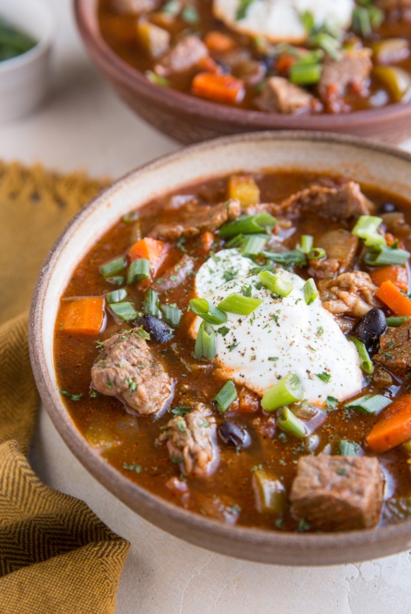 Two large bowls full of steak chili with beans and fresh vegetables. Ready to serve.